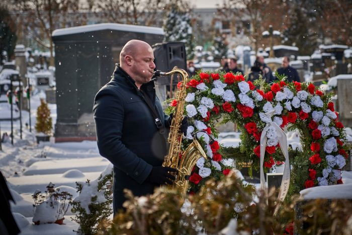 Saxofonista hrající při pohřebním obřadu na hřbitově.